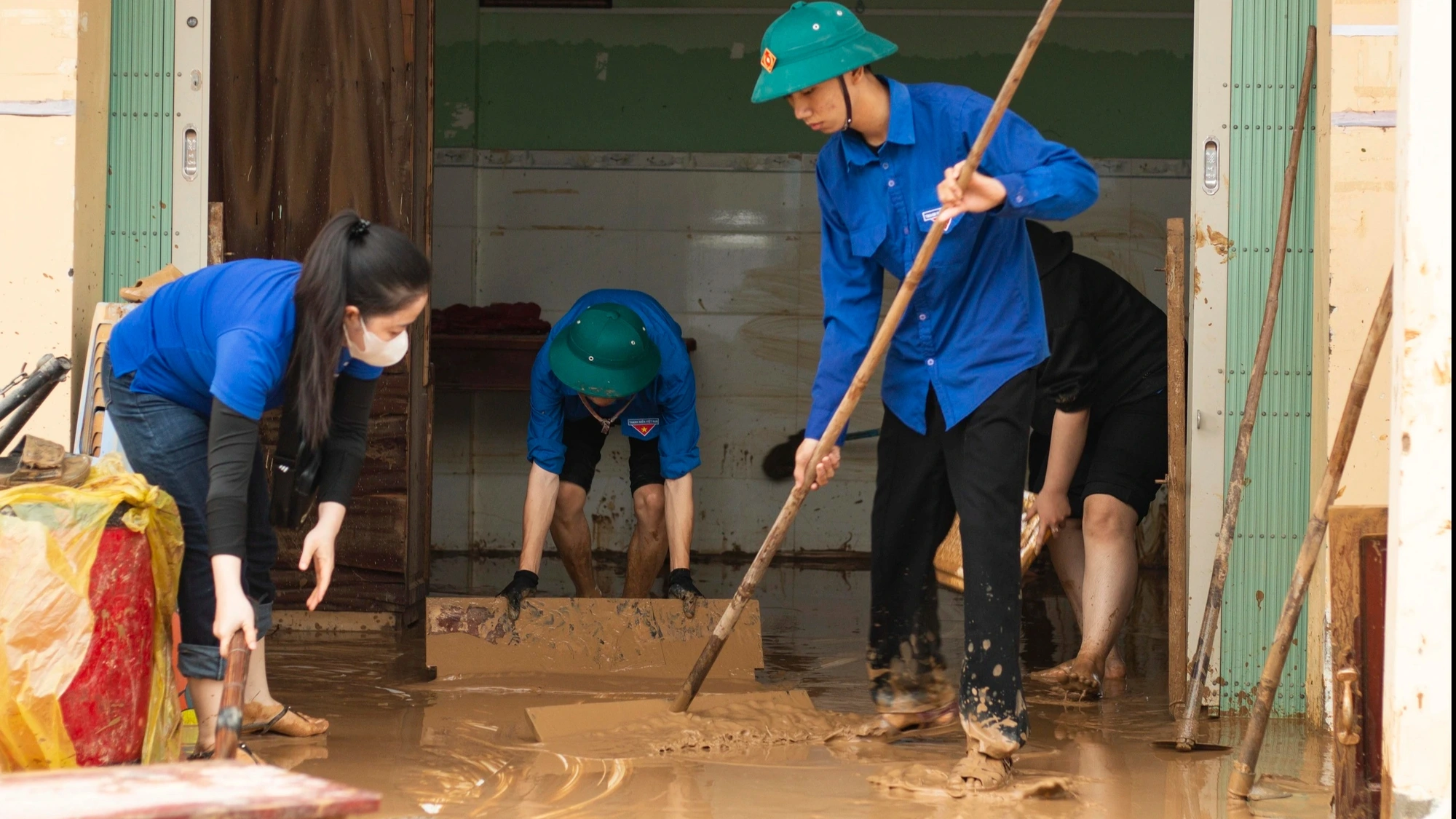 Thanh niên đội mưa, ngâm nước lũ giúp dân dọn nhà cửa, quét bùn đất